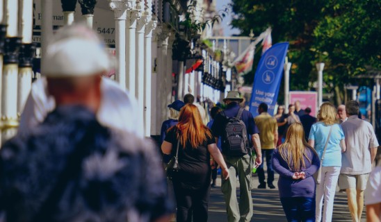 Busy street scene with pedestrians walking along a sunny promenade.