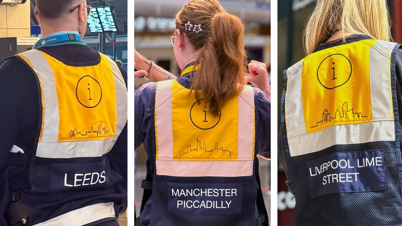 Three workers seen from behind wearing high-visibility jackets with i logos and city skyline drawings.