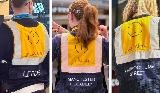 Three workers seen from behind wearing high-visibility jackets with i logos and city skyline drawings.
