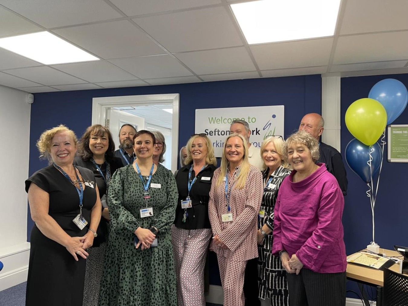 Group of people indoors posing for photo in office reception area.
