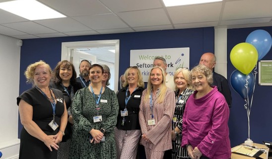 Group of people indoors posing for photo in office reception area.
