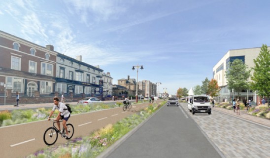 Bright street scene with cyclists on a dedicated bike lane and pedestrians on the pavement.