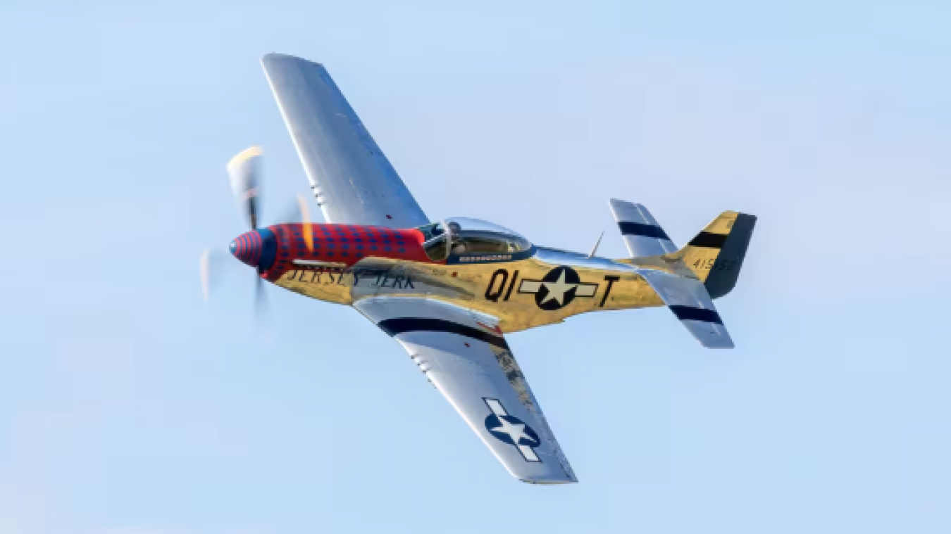 Propeller aircraft in flight with yellow and blue paint and U.S. star insignia against blue sky