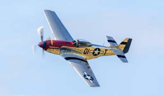 Propeller aircraft in flight with yellow and blue paint and U.S. star insignia against blue sky