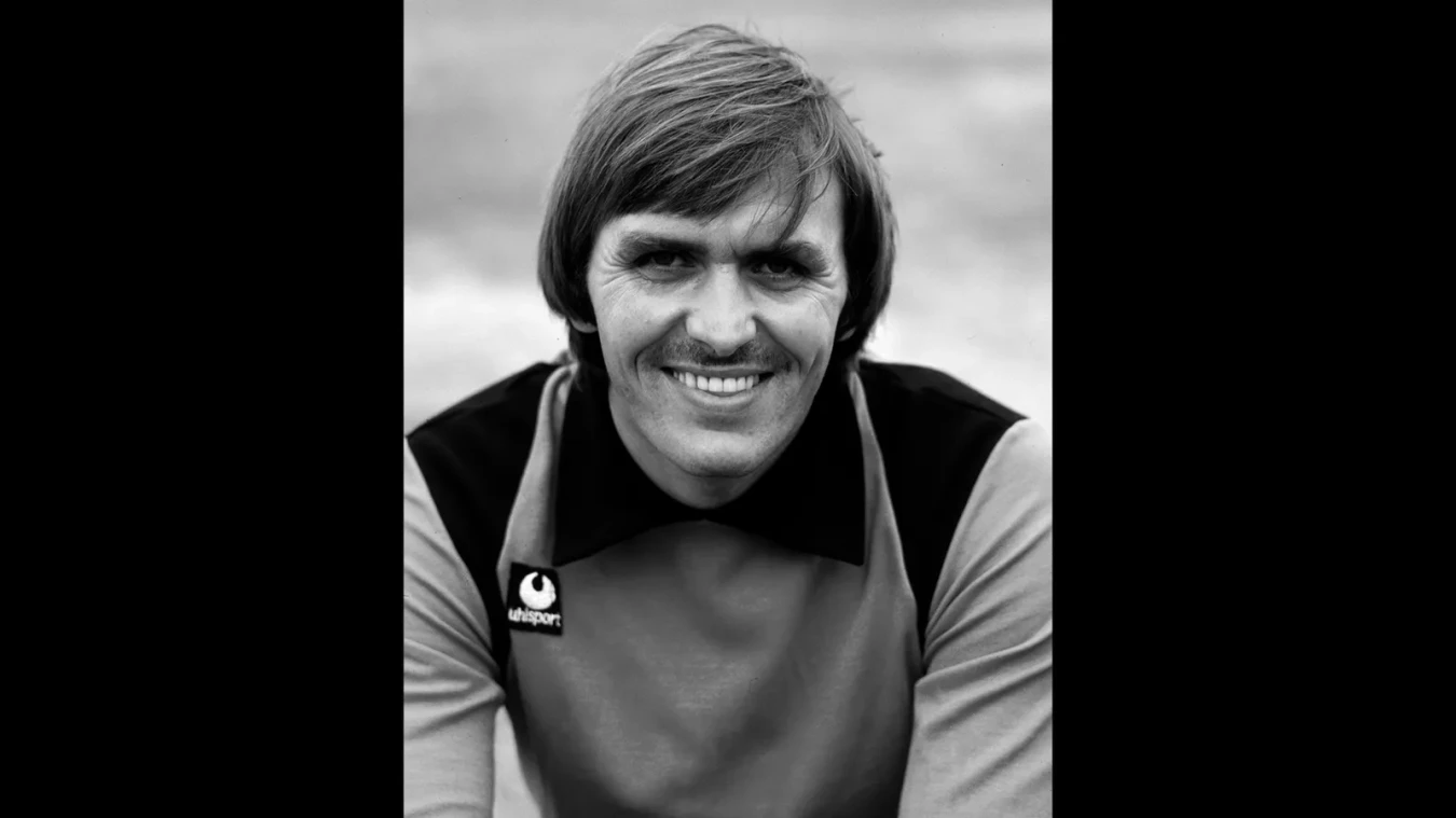 Smiling man with short hair in a vintage Lifesport shirt, black and white portrait.