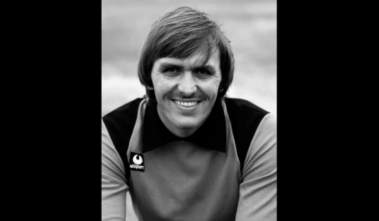 Smiling man with short hair in a vintage Lifesport shirt, black and white portrait.