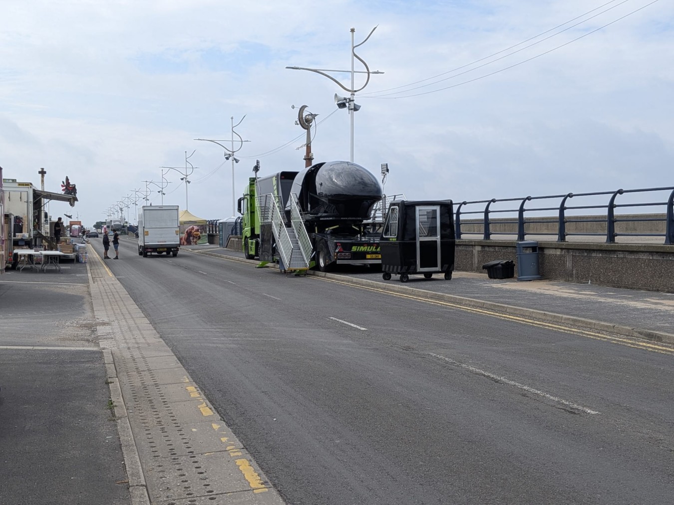 A pier roadway with a line of service vehicles and blank stalls, sky visible with clouds.