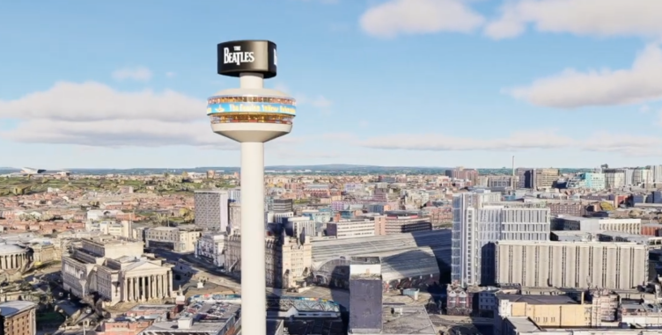 Aerial view of a city with a tall observation tower in the foreground featuring a circular top adorned with a Beatles sign.