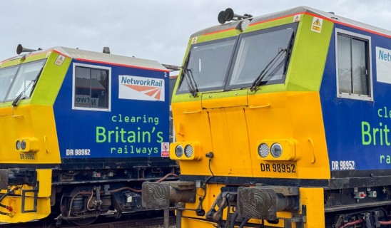 Two bright Network Rail diesel locomotives painted in blue and yellow parked side by side