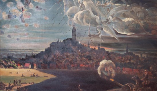 Large historical painting showing a battle around a hilltop town with smoke, cannons, and soldiers in foreground.
