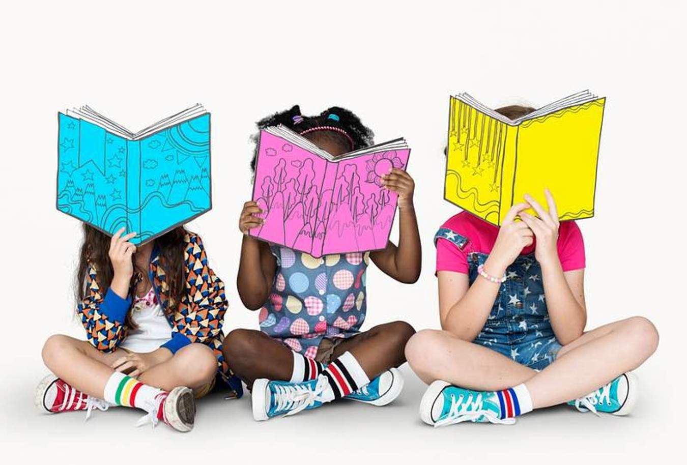 Three children sitting cross-legged, reading colourful illustrated books over their faces.