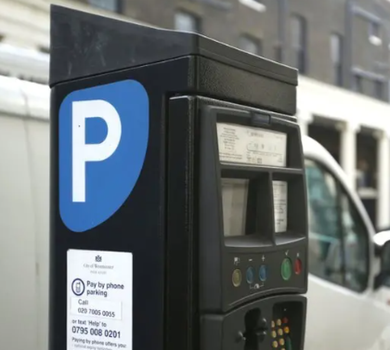 Parking meter with blue P sign in foreground; blurred urban street in background
