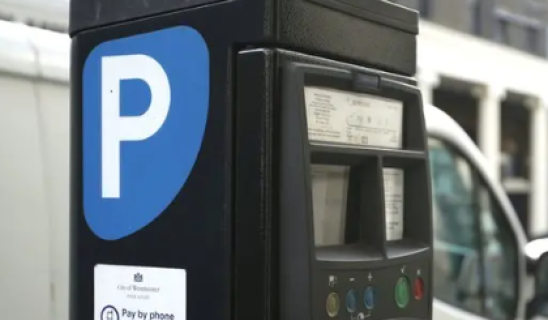 Parking meter with blue P sign in foreground; blurred urban street in background