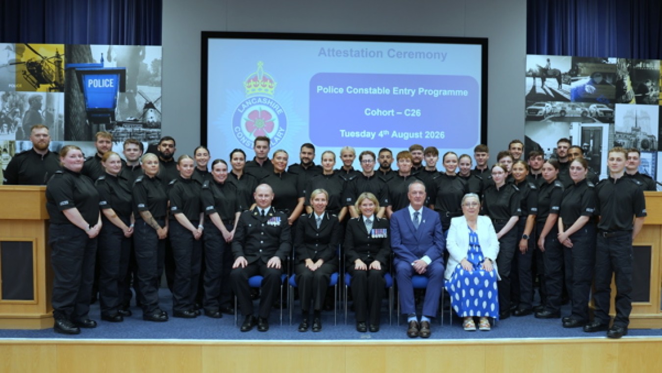 Police cadets in black uniforms posing with dignitaries on stage during ceremony.