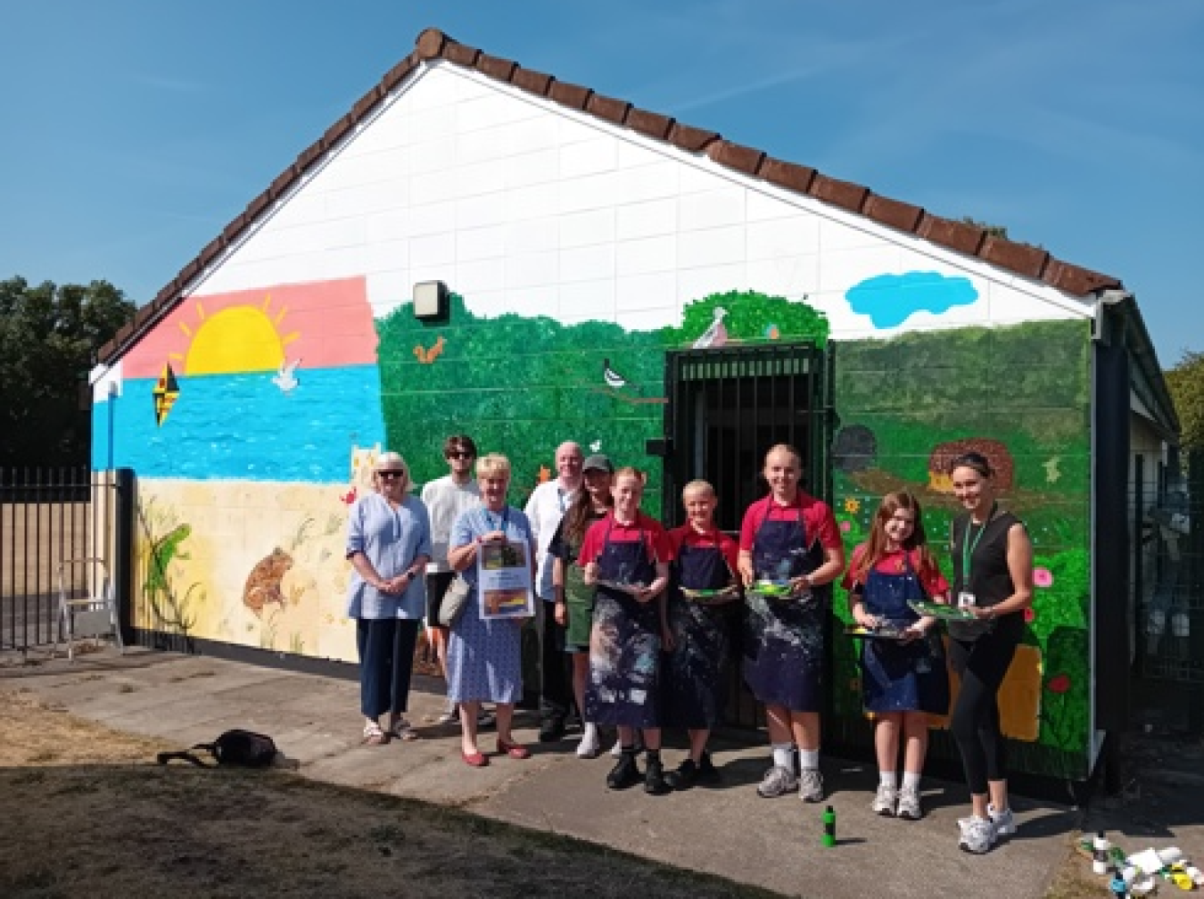 Group of people standing in front of a colourful mural on a building