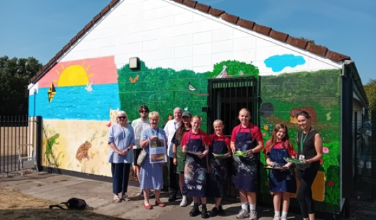 Group of people standing in front of a colourful mural on a building