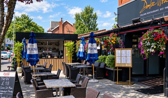 Curbside Italian restaurant with outdoor seating and blue Peroni umbrellas