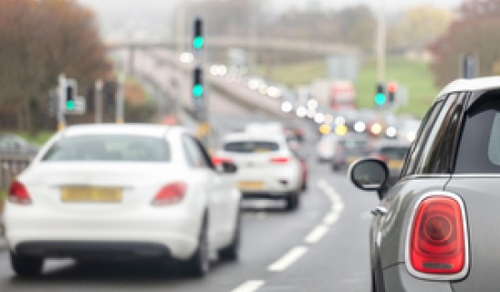 Urban road with cars in traffic and traffic lights ahead