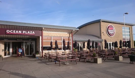 Ocean Plaza exterior with outdoor seating and Brewery's logo, clear blue sky