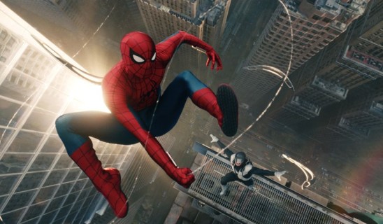 Spider-Man swings between tall city buildings at dusk with a companion on a ledge