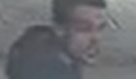 Blurred man walking outdoors, indistinct features visible