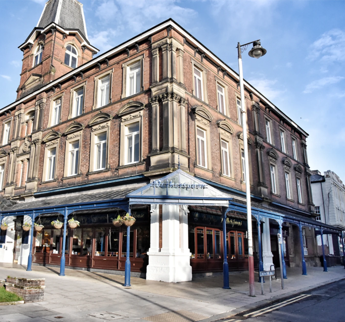Terraced brick hotel building with blue awning on ground floor and hanging flower baskets