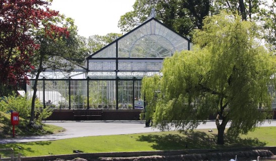 Glasshouse conservatory surrounded by trees and a grassy area by a path