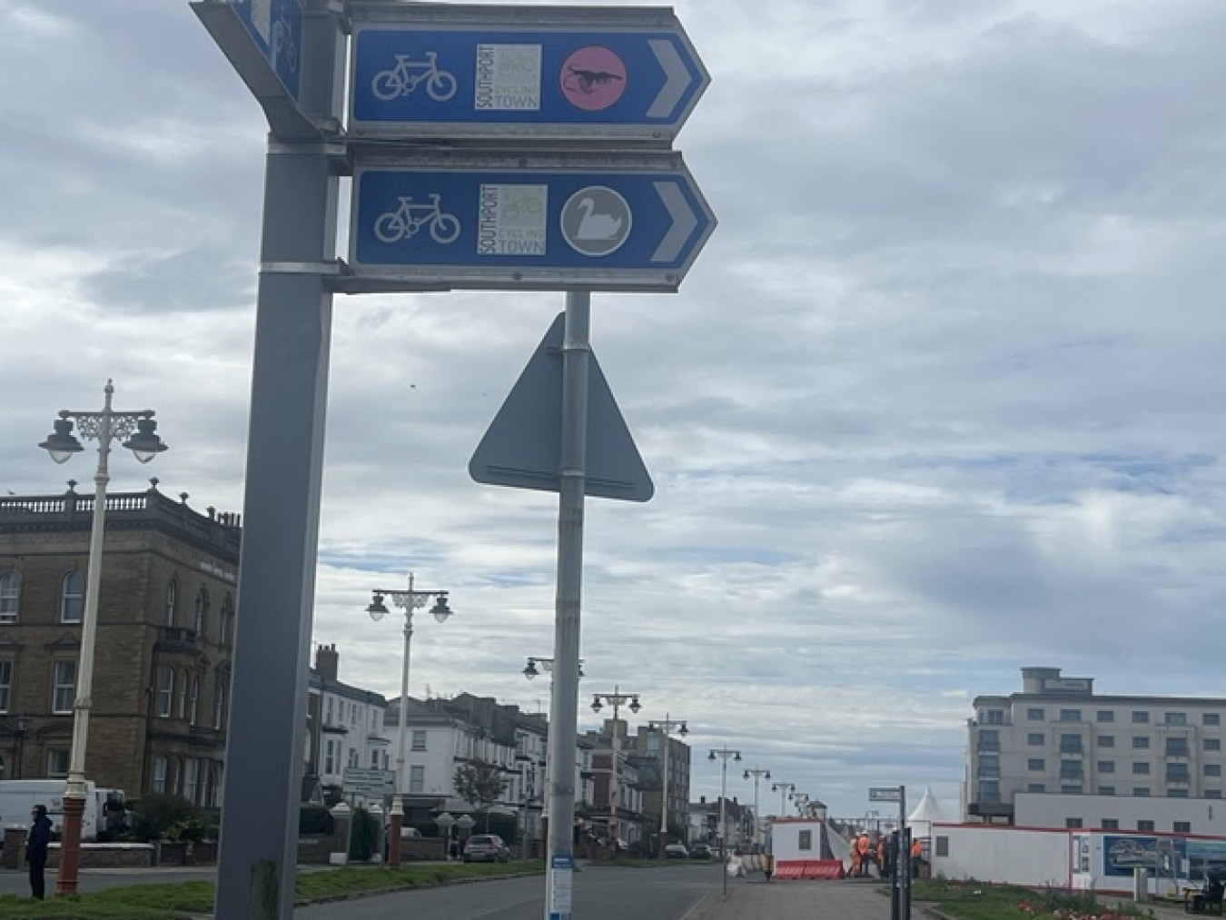 Signs directing cyclists and pedestrians along a seaside town street with historic buildings