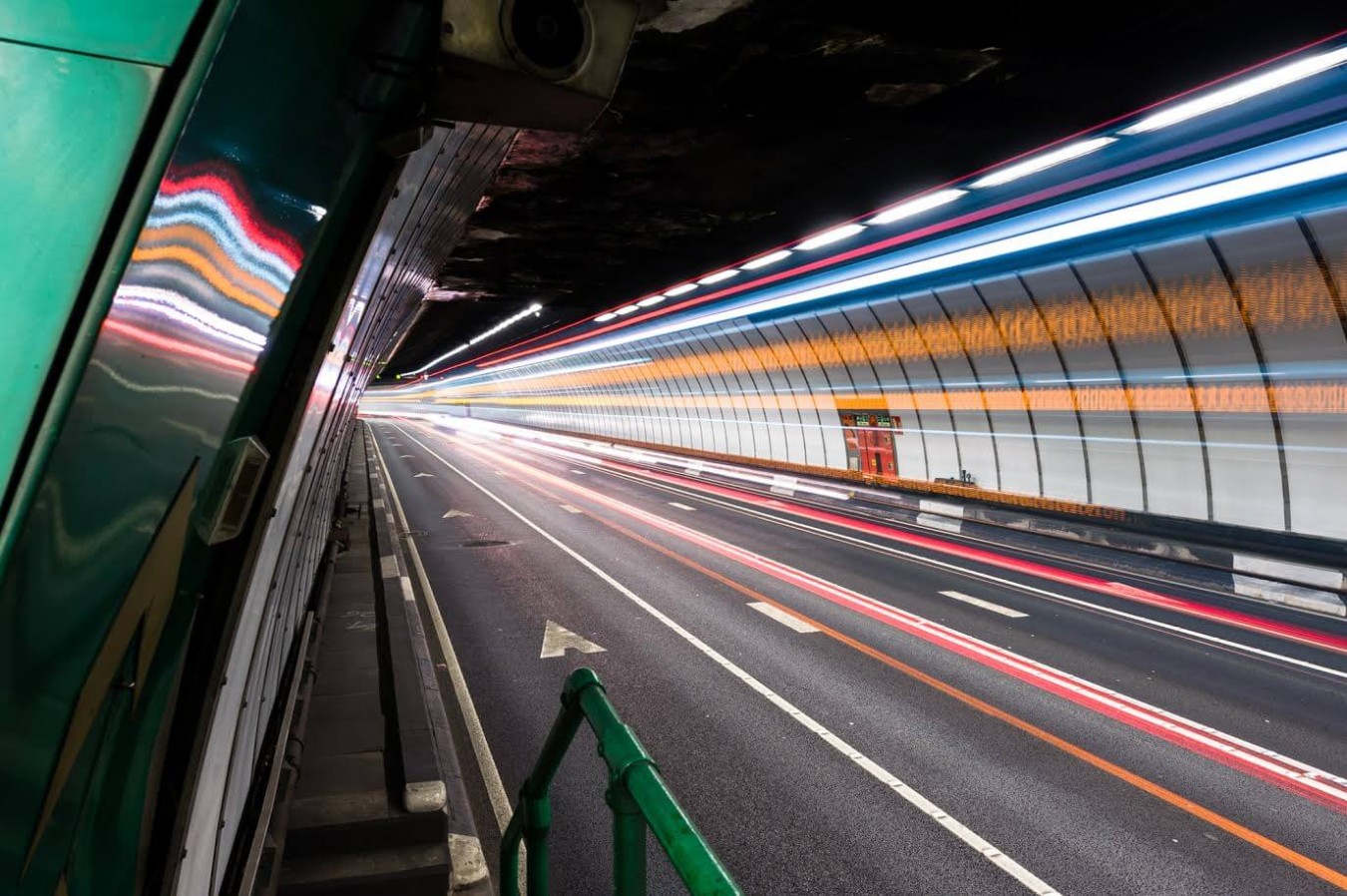 Long exposure of a tunnel with light trails from passing vehicles along a curved roadway