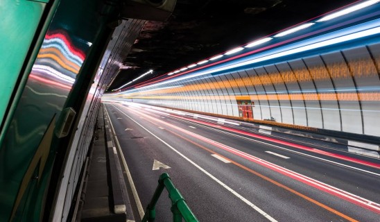 Long exposure of a tunnel with light trails from passing vehicles along a curved roadway