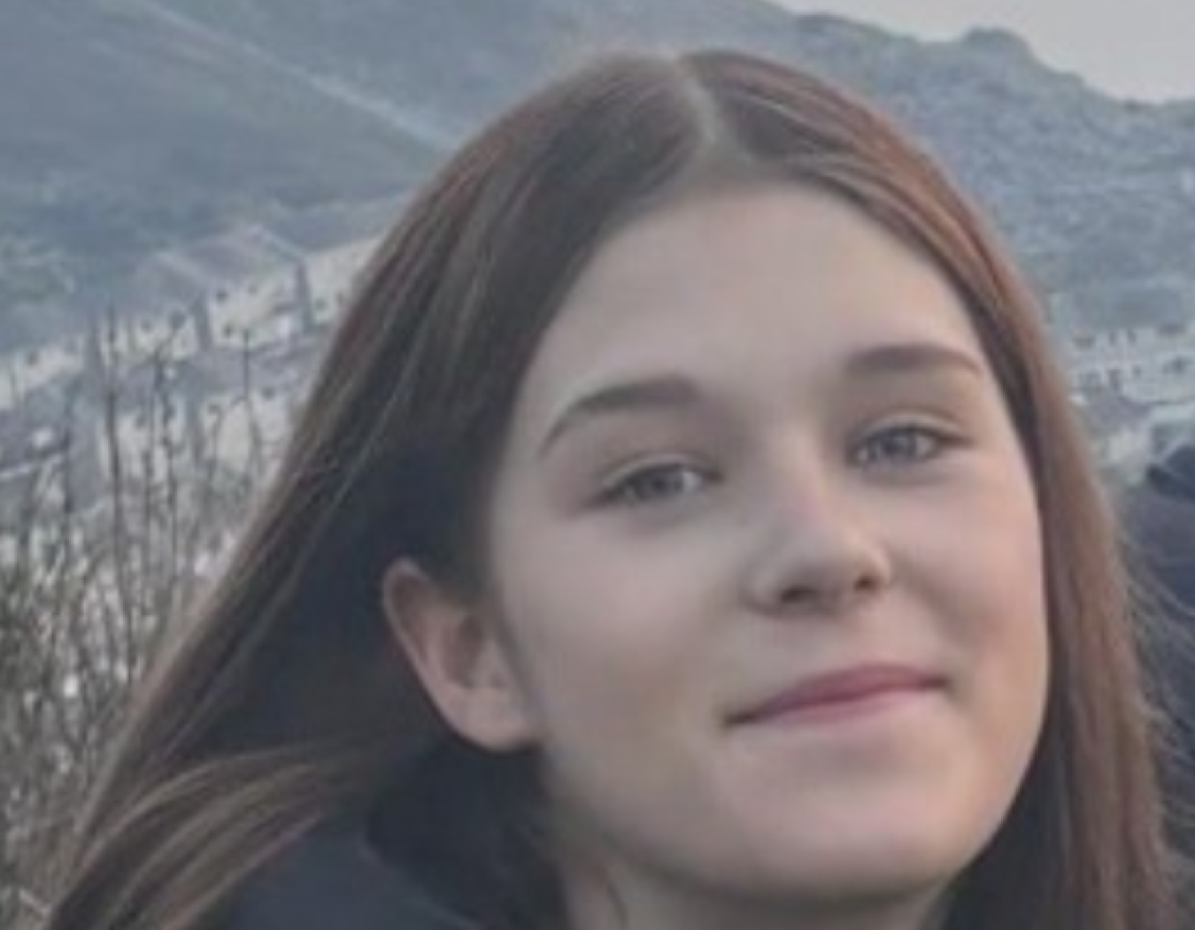 Young woman's face in close-up with hillside background