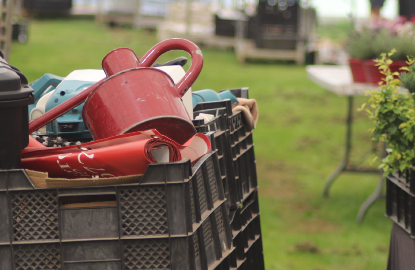 Plastic crates filled with assorted garden tools and pots outdoors in a yard