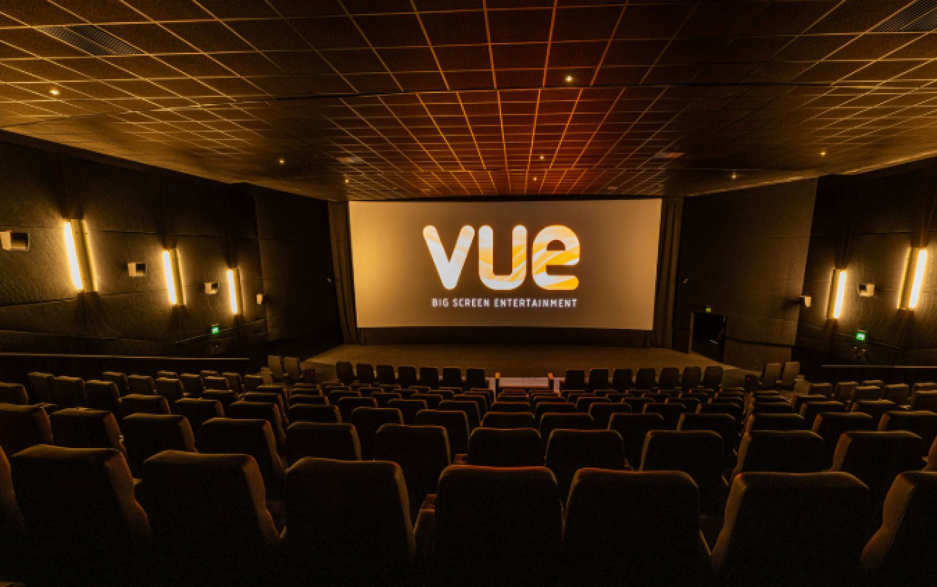 Empty cinema auditorium with large screen showing 'Vue' logo and seating rows in warm lighting